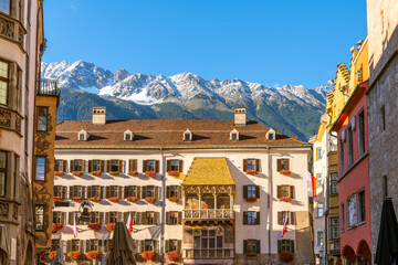 Snow capped mountains in early autumn above the historic Goldenes Dachl or Golden Roof in the medieval old town of Innsbruck, Austria, in the Austrian Alps. - obrazy, fototapety, plakaty