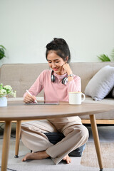 Pretty Asian female college student doing homework in her living room.