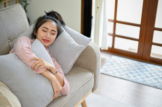 Beautiful Asian female sleeping or taking nap on her comfortable sofa in her living room.