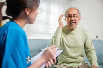 Asian elderly man patient have headache and female nurse talking, checking up and recording current symptoms on clipboard in living room, Home healthcare and medical service