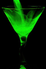 Pouring glowing green liquid into cocktail glass