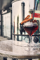 Festive hot drink mulled wine for New year and Christmas on the street in a glass. Vertical photo.