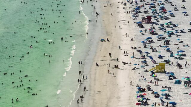 Aerial seascape with Siesta Key sandy beach in Sarasota, USA. Many tourists enjoing summer vacation time swimming in warm Mexico gulf water and sunbathing on hot Florida sun