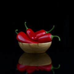Red hot chili pepper in a wooden bowl on a black background. Photo.