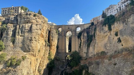 Puente Nuevo bridge over Guadalevin River with a blue cloudy sky in the background, Ronda, Spain