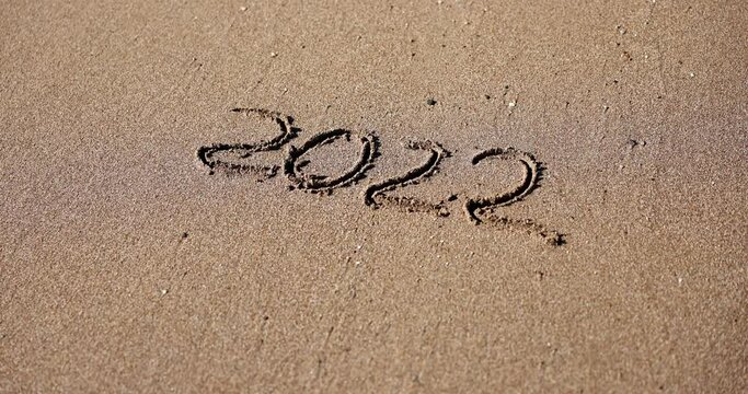 New year 2022 concept. Top view of numbers 2022 written on sand coastline