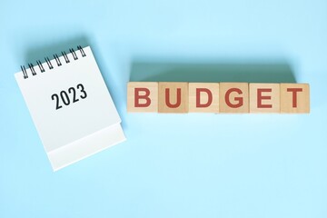 Year 2023 budget and budgeting concept. Desk calendar flat lay on blue background.