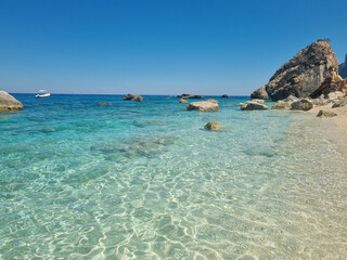 Fototapeta premium crystal clear water at beach cala dei gabbiani with lonesome speedboat, sardegna, 