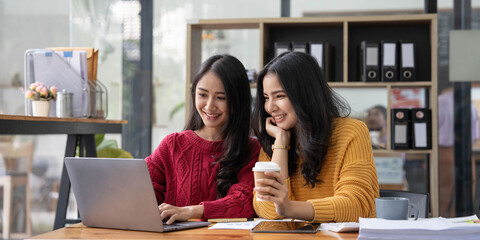 Two young Asian business woman talk, consult, discuss working with new startup project idea...
