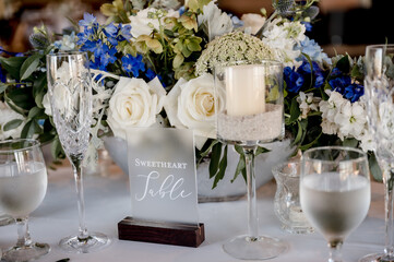 Sweetheart sign on table with blue and white wedding floral centerpiece on white table cloth...