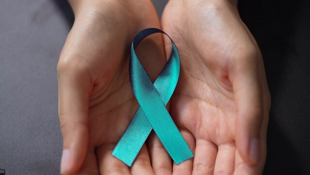 Close-up Of A Human Hand Showing Teal Ribbon