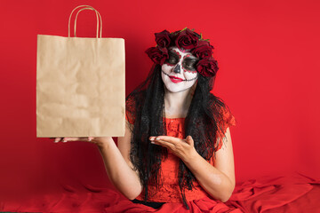 Portrait of a young woman in a red dress and traditional sugar skull makeup for the celebration of Dia de los Muertos, the Day of the Dead