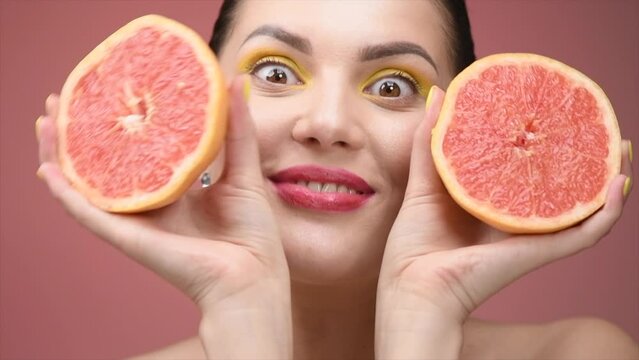 Healthy eating, diet. Beautiful healthy girl with slices of red grapefruit, food, cosmetics concept. Beauty young woman plays with grapefruits, smiling. Organic vegetables. Vegetarian. Detox concept