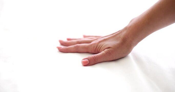 Closeup seductive female hand touching soft white sheet and blanket on bed