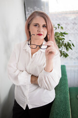 Portrait of an adult woman entrepreneur with grayish hair in a managerial position, dressed in a white blouse and busy working in the office