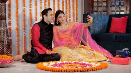 A married couple happily waving and chatting on a video call during Diwali