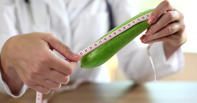 Green cucumber doctor measures with measuring tape indicates length of male penis