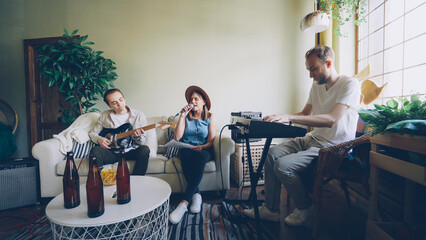 Pretty blond vocalist is singing looking at paper with lyrics while her friends are playing musical...