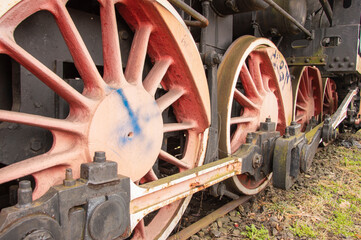 Drive transmission mechanism in a historic and damaged steam locomotive standing on a sidetrack. Rail.