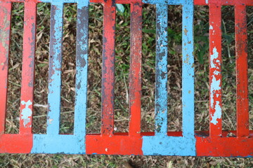 iron trellis with red and blue paint that has peeled off