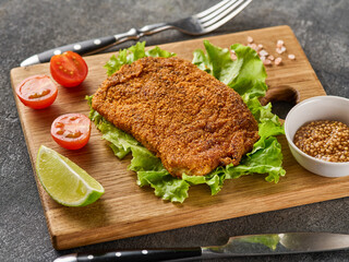 Breaded pork cutlet with cherry tomatoes, mustard and lemon.