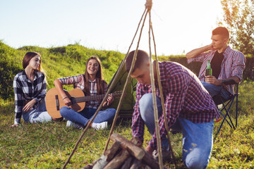 Young people having picnic, girl playing guitar