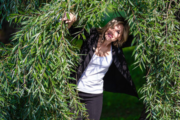 Young beautiful woman laughing and fooling around in the willow branches