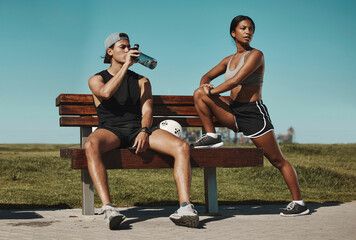 Obraz na płótnie Canvas Sports, bench and fitness people with water bottle in a park for outdoor training, workout or wellness with blue sky mock up. Athlete or runner couple relax together after running with summer mockup