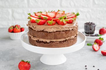 Naked chocolate cake with cream and fresh strawberries on top. Rustic style. Selective focus. Copy space.