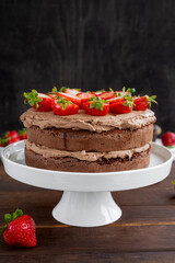 Naked chocolate cake with cream and fresh strawberries on top. Rustic style. Selective focus. Copy space.