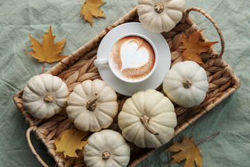 Fototapeta na wymiar White pumpkins, coffee and autumn leaves on a wicker tray.