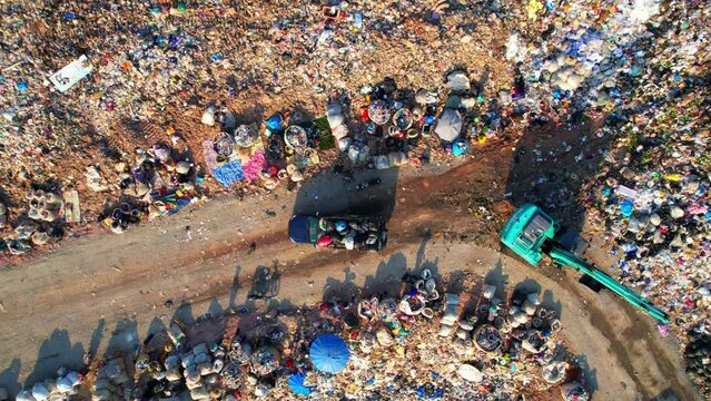 4K : Aerial view from a drone flying over a large pile of garbage, garbage dump with plastic bags. workers and machines are working. Environmental pollution.
