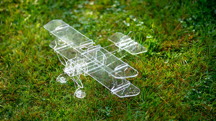 A paraglider with two plastic wings stands on green grass. An airplane model made of plastic...
