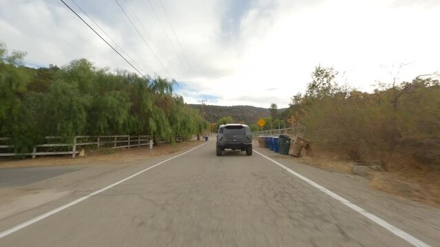 FPV follow shot of a Rezvani driving and braking on a town road in California.
