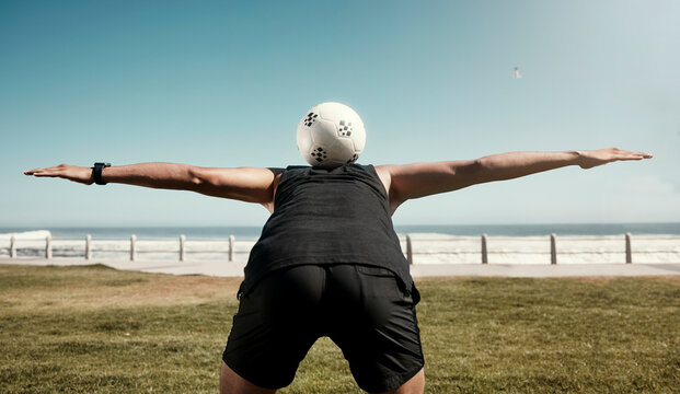 Soccer ball, balance back and sports training of a man athlete at the beach for a workout. Exercise, fitness and health cardio of a person on a field by sea water, ocean and nature in summer - Powered by Adobe