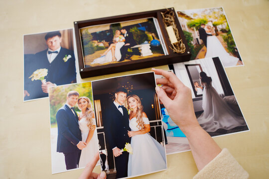 printed wedding photos in the hands and in a wooden box with a flash drive. 