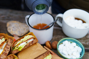 picnic in the autumn season, food on a wooden table, hot tea, pastries and sandwiches