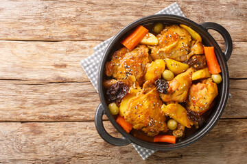Gallo en chicha is a rooster cooked in a fermented corn drink with vegetable and spices closeup on the pan on the wooden table. Horizontal top view from above