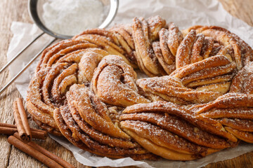 Kringle or pretzel traditional Christmas dessert in Northern Europe with cinnamon closeup on the paper on the wooden table. Horizontal