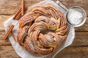 Kringle or pretzel traditional Christmas dessert in Northern Europe with cinnamon closeup on the paper on the wooden table. Horizontal top view from above