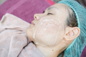 White Asian woman with eyes closed To apply a clear gel on the face, to do facial treatments, in beauty clinics.