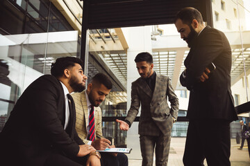 Business partners jointly discuss the difficulties and the implementation of ideas. Young successful men in suits at a team meeting outside the office