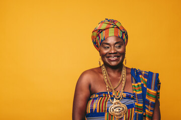 Smiling Ghanaian woman wearing elegant traditional clothing in a studio