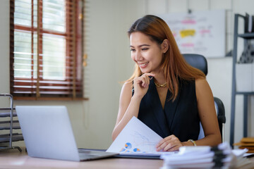 Young  Asian businesswoman who is happy to work in the office with a lot of paperwork arranged on the desk.