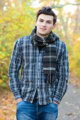 Young handsome teenage man walking in autumn park