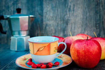 Tea with apples and rose hips on a wooden table. Autumn still life