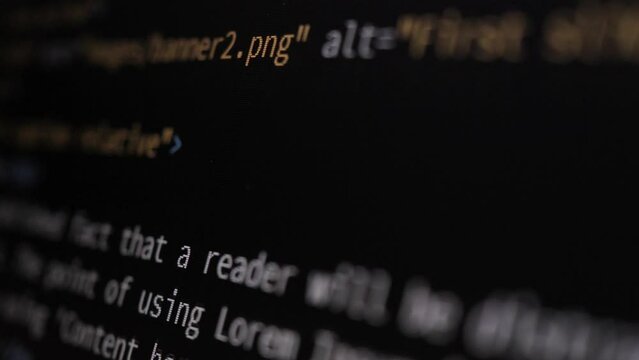 4K Close-up shot HTML tag code on PC Monitor scroll down. Background concept for programming and coding web development. Side view, macro static shot. Orange and blue letters.