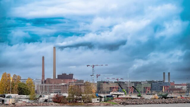 Amazing skyline of the city harbour with factory chimneys. Beautiful clouds moving and dockworkers working around a boat. 