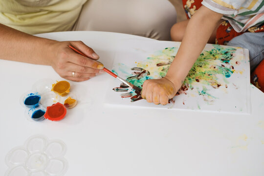 Child with cerebral palsy painting with fingers and hands. close-up, boy with disability developing fine motor skills. Education for children with mental and physical disorders, sensory therapy game.