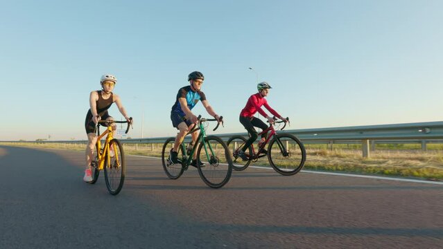 Sport people in activewear and helmets using professional bikes for cycling on fresh air. Caucasian men and woman enjoying active time spending outdoors.